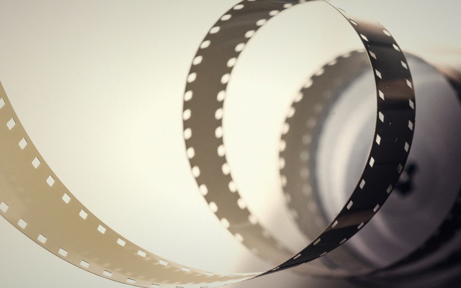 A curled strip of perforated film unspooling in a loose swirl