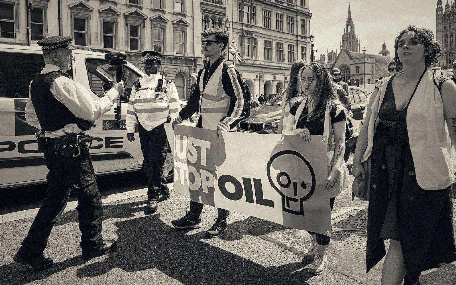 Police officers film Just Stop Oil protesters carrying a banner near Westminster